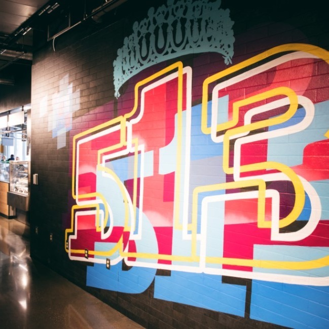 Colorful mural displaying the numbers "513" with vibrant patterns, highlighting urban art's role in the space's aesthetic and cultural identity.